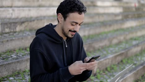 Smiling-man-using-smartphone-on-street